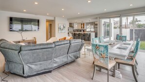 Een moderne woonkamer met een grijze modulaire bank, een eettafel met stoelen en een keuken op de achtergrond.