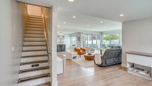 Een modern interieur met een trap, een zithoek met banken, een eettafel en een keuken op de achtergrond.