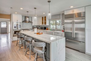 A modern kitchen with a central island, bar stools, stainless steel appliances, and pendant lighting. - Upscale Huntington Beach Home, Close to Main St! (Huntington Beach)