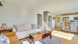 Una sala de estar moderna con sofá, mesa de centro y zona de cocina con armarios y nevera.