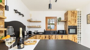 Ett modernt kök med en svart bänkskiva, träskåp, en inbyggd ugn och ett fönster.