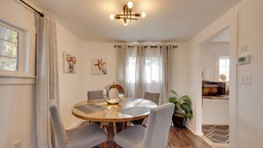 A dining area with a round wooden table, four grey upholstered chairs, a decorative mirror, and a chandelier. - 2 Mi to Dtwn: Colorado Springs Gem w/ Hot Tub! (Colorado Springs)