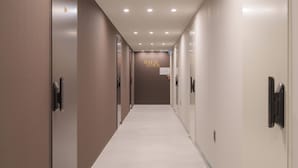 Un pasillo largo de hotel, con puertas a ambos lados y un cartel en la pared al fondo.