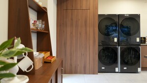 Una cocina moderna con armarios de madera, un estante empotrado con cristalería y una lavadora-secadora de doble puerta.