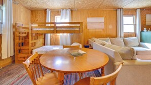 Une pièce chaleureuse avec un lit superposé, une table ronde en bois et un canapé.