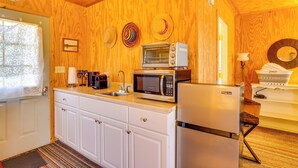 Une cuisine avec des murs en bois, un plan de travail blanc, un four à micro-ondes, un réfrigérateur et un évier.