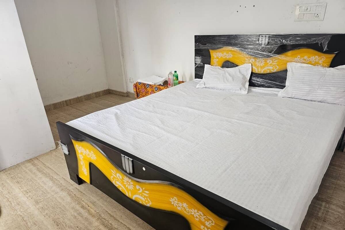 Un letto con materasso bianco e struttura nera decorata con motivi floreali gialli.