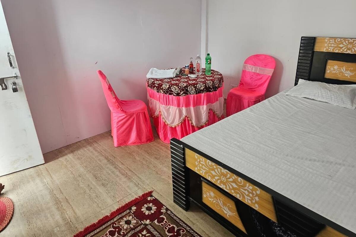 Una camera da letto con un letto, un tavolino e sedie, e una tovaglia a quadri rossi e bianchi.