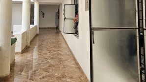 A corridor with marble flooring, white walls, and a large glass door with a metal frame. - Lama Hotel Barabar (Jahanabad)