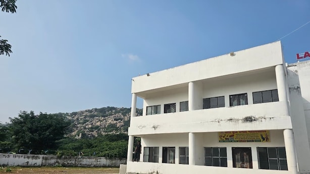 A white multi-story building with a signboard on the ground floor. - Lama Hotel Barabar (Jahanabad)