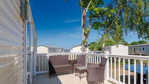 A covered outdoor area with wicker furniture and a white railing. - 3 Bed Caravan - Seton Sands (Prestonpans)