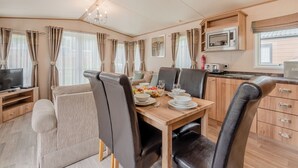 A compact, well-lit room with a dining table set for two, a television, and a kitchenette area. - Superb and spacious lodge with one double, one twin and one single. (Bala,)