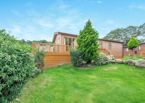 A wooden deck, a large evergreen tree, and a small building with a window. - 1 bedroom accommodation in Bala, (Bala,)