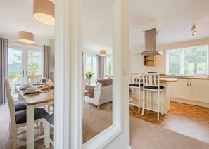 A modern interior with a dining area, kitchen, and a view through a doorway. - 1 bedroom accommodation in Bala, (Bala,)