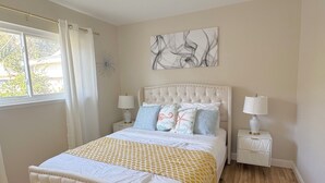 Una camera da letto con un letto grande, due comodini, una finestra con tende e una lampada a soffitto.