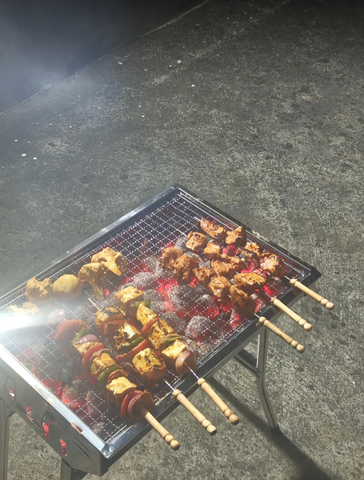Una parrilla con diversas carnes y verduras asándose.