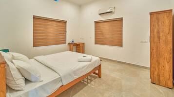A bedroom with a bed, wooden wardrobe, and an air conditioning unit on the wall.