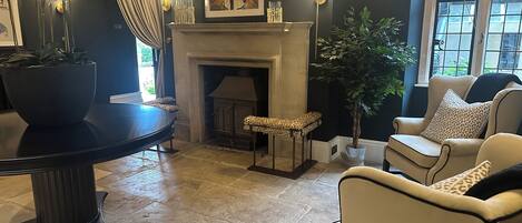 Una sala de estar con chimenea, una mesa redonda y dos sillones.