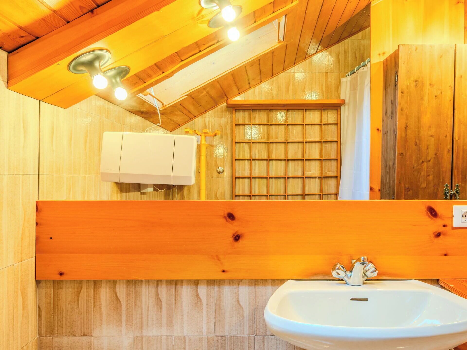 Ein Badezimmer einer Holzhütte mit einem weißen Waschbecken, Holzschränken und einem Spiegel.