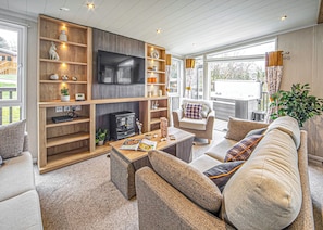Un salon chaleureux avec une cheminée, des étagères en bois, un canapé et un téléviseur.