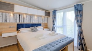 Un dormitorio moderno con una cama grande, cabecera de madera, un banco empotrado y vistas al exterior.