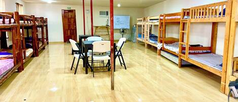 Un dormitorio con literas, una mesa de comedor con sillas y una pizarra en la pared.
