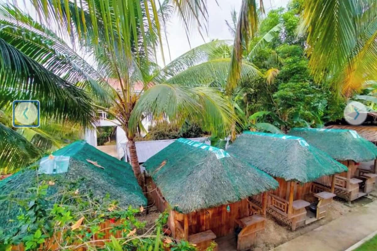 A rustic wooden structure with thatched roofs and a small wooden bench.