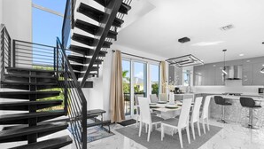 A modern kitchen with a central island, a dining area with white chairs, and a staircase with black railings. - Copa D Oro 835 in Marathon (Marathon)