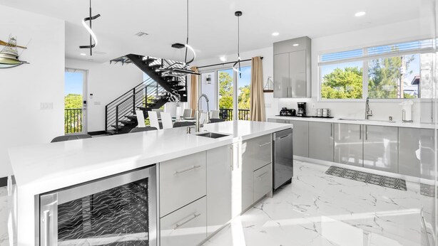 A modern kitchen with a central island, stainless steel appliances, and a black spiral staircase. - Copa D Oro 835 in Marathon (Marathon)