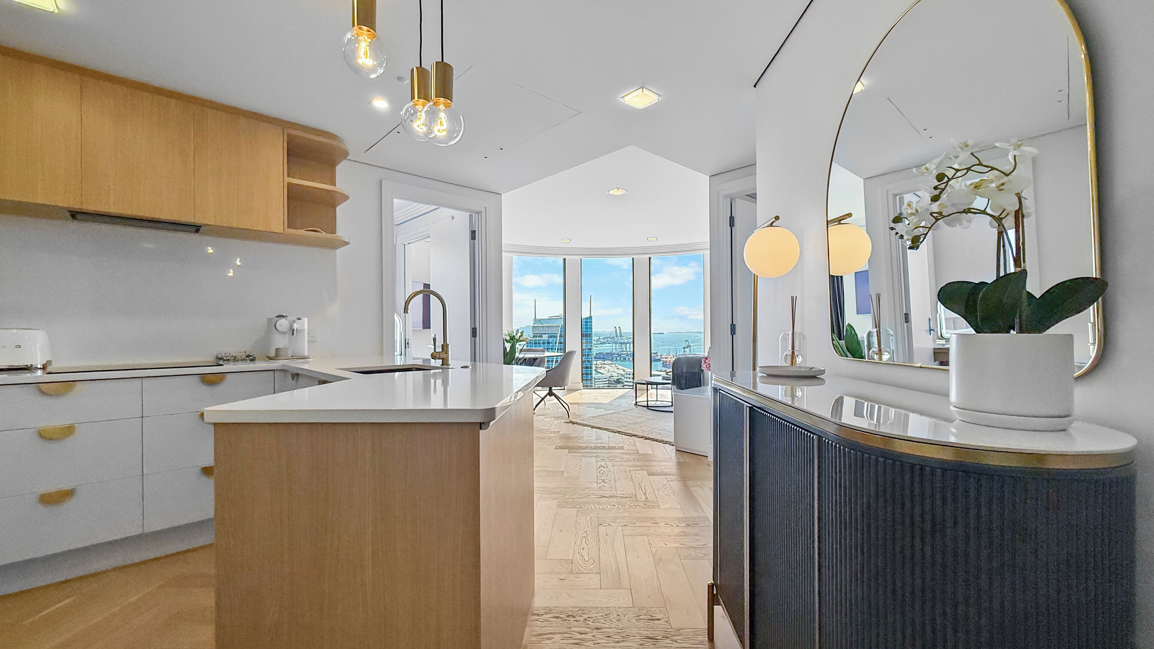 A modern kitchen with a central island, wooden cabinets, and pendant lighting.