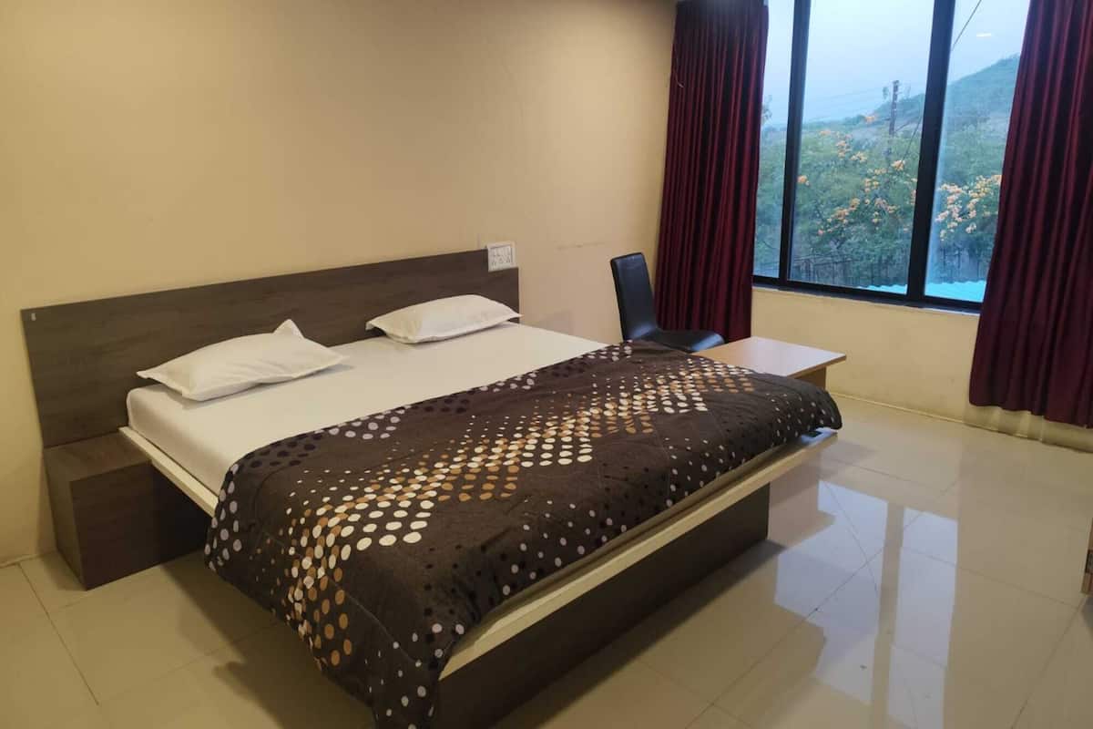 A neatly made bed with a patterned bedspread, a bedside table, and a chair.