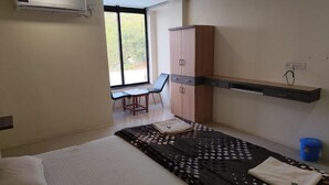 Una habitació d'hotel amb llit, escriptori, cadira, armari i finestra.