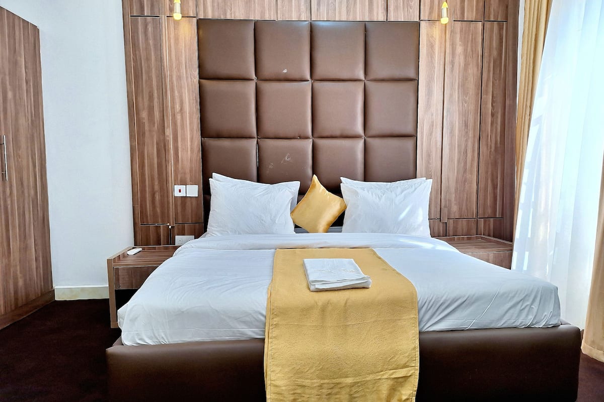 Ein Hotelzimmer mit einem großen Bett, einem Holzkopfende und einem Nachttisch.