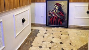 A hallway with wooden paneling, a framed painting, and a patterned floor. - Luxxe Suites By Almond (Abuja)