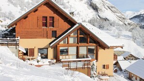 A wooden chalet with a sloped roof, large windows, and a balcony. - Apartment in Serroz Near Ski Lift (Valloire)