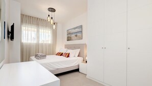 A modern bedroom with a bed, bedside tables, a TV, and a wardrobe. - Beautiful new build apartment Estepona - Estepona, Andalucía (Estepona)