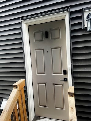A door with a simple design, a small mailbox, and a wooden handrail. - Peaceful Homes | Elegant 2 Bedroom Suite (Calgary)