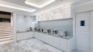 A modern kitchen with marble flooring, white cabinetry, and built-in shelves. - Emerald Luxe A Boutique Hotel (Mohali)