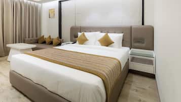 A modern hotel room with a large bed, a bedside table, a small table, and a sofa.