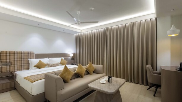 A modern hotel room with a bed, sofa, and a small table. - Emerald Luxe A Boutique Hotel  (Mohali)