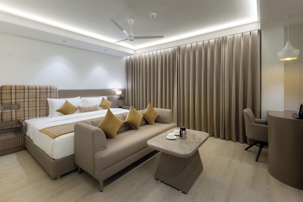 A modern hotel room with a bed, sofa, and a small table.