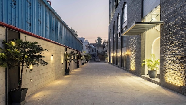 A narrow alleyway with a paved path, flanked by buildings with exposed brick and blue insulation. - Emerald Luxe A Boutique Hotel (Mohali)