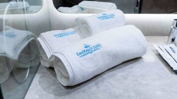 Neatly folded white towels with "Emerald Luxe Boutique Hotel" branding on a marble countertop.