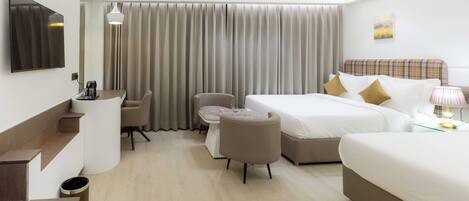 A hotel room with a bed, a desk with a chair, a sofa, a TV, and a window with curtains.