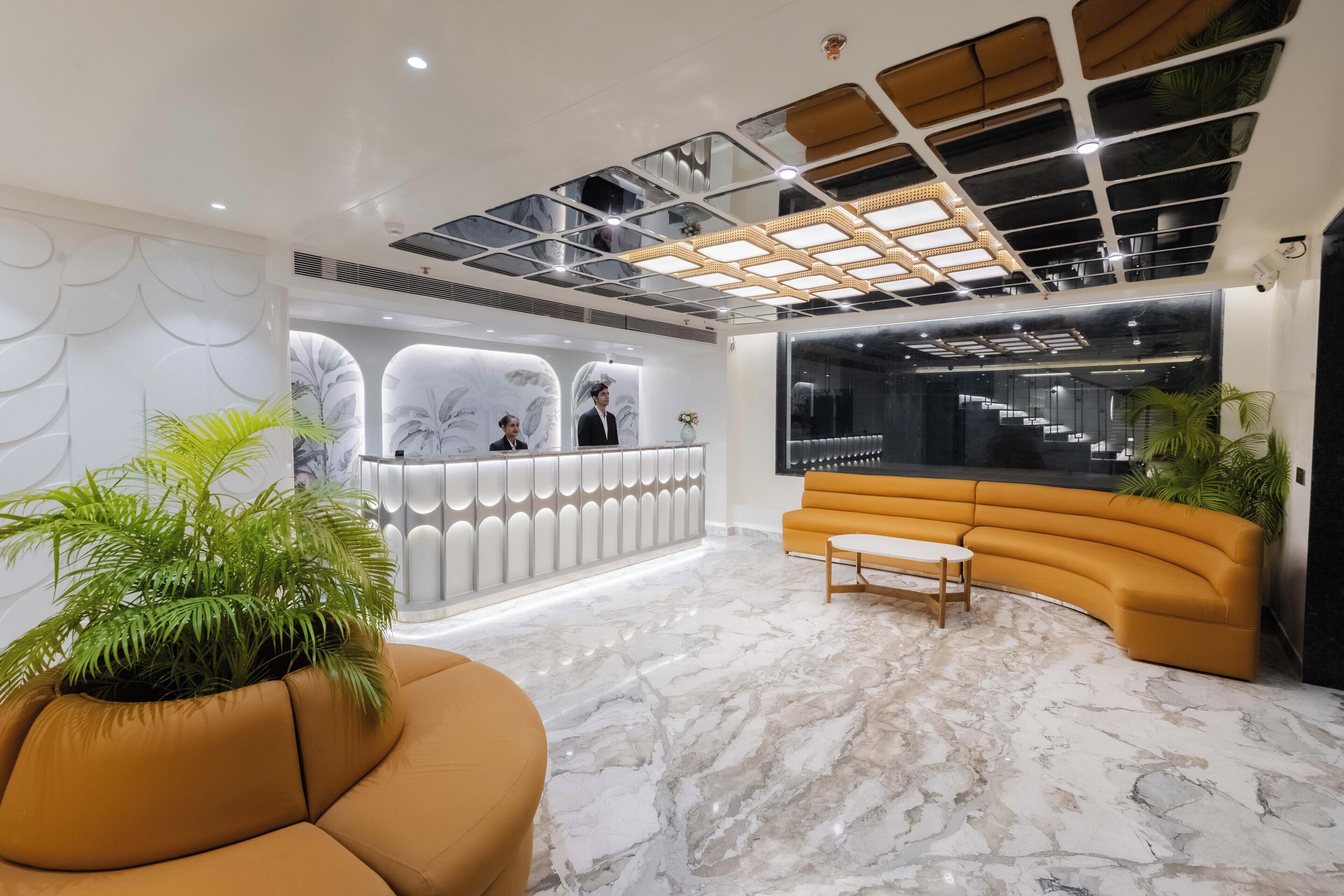 En moderne lobby med en receptionsdisk, en buet sofa og en potteplante.