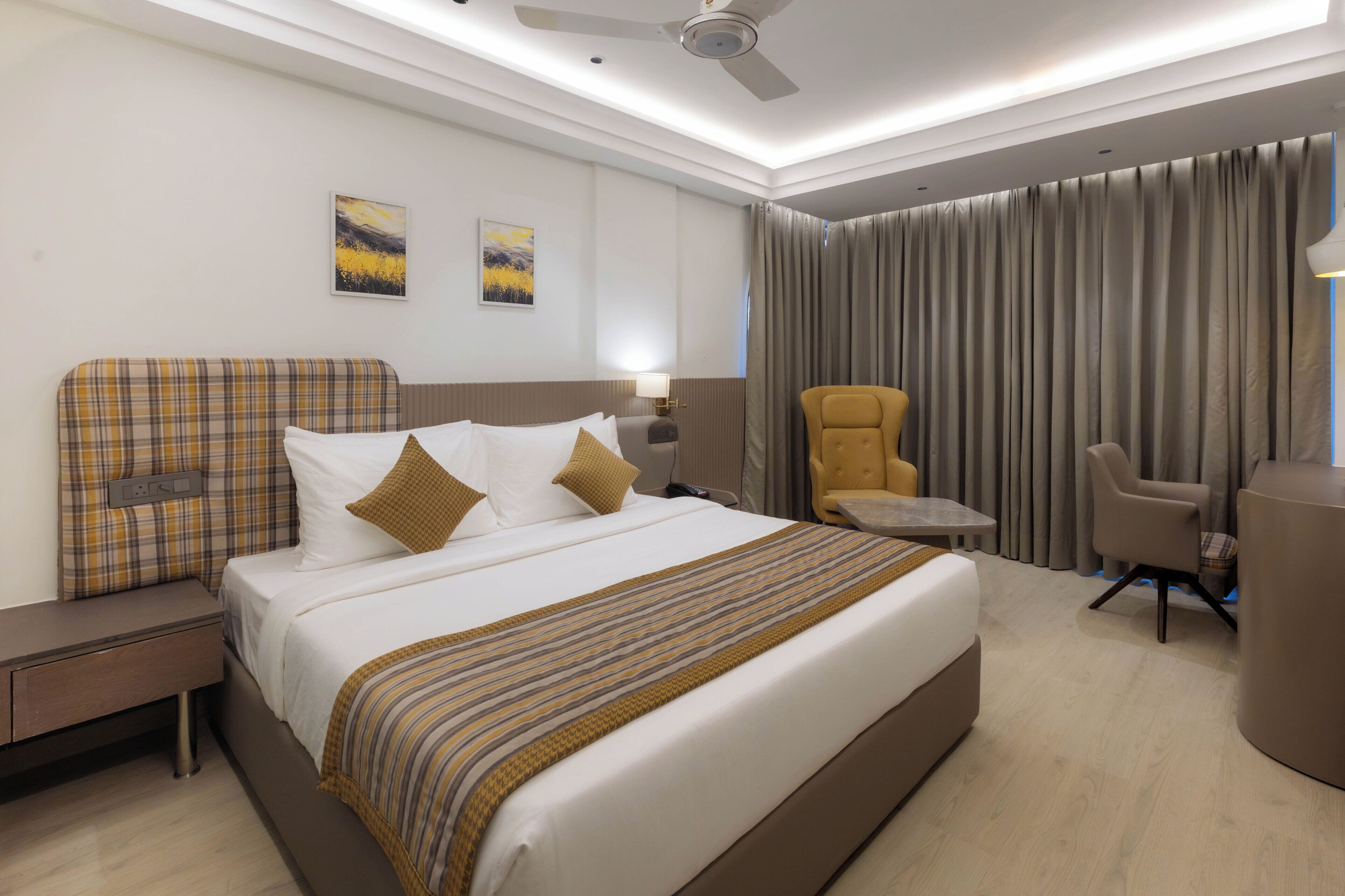 Habitación de hotel con una cama grande, un escritorio, una silla y un ventilador de techo.