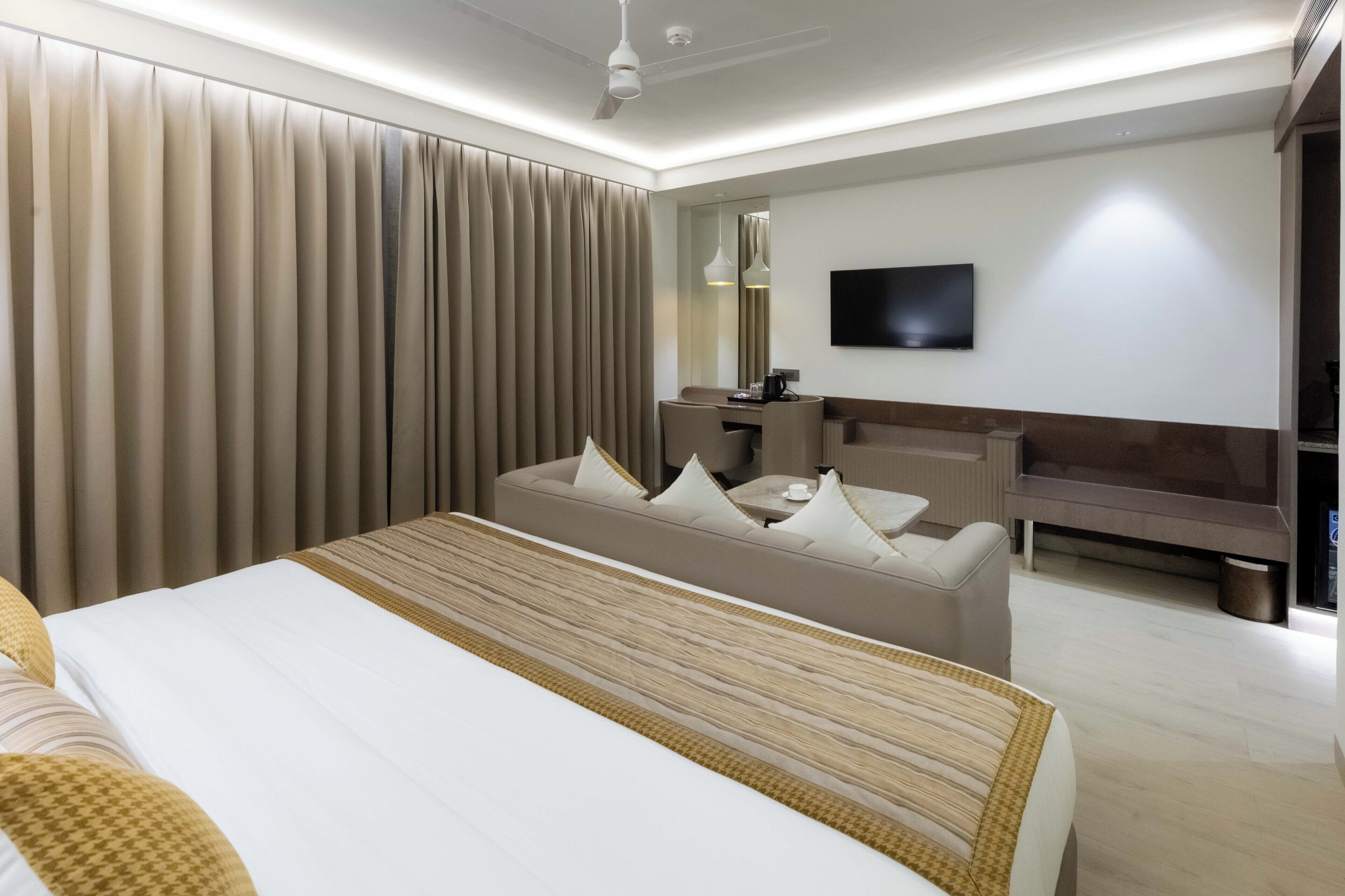 Une chambre d’hôtel moderne équipée d’un grand lit, d’un canapé, d’un bureau et d’une télévision.