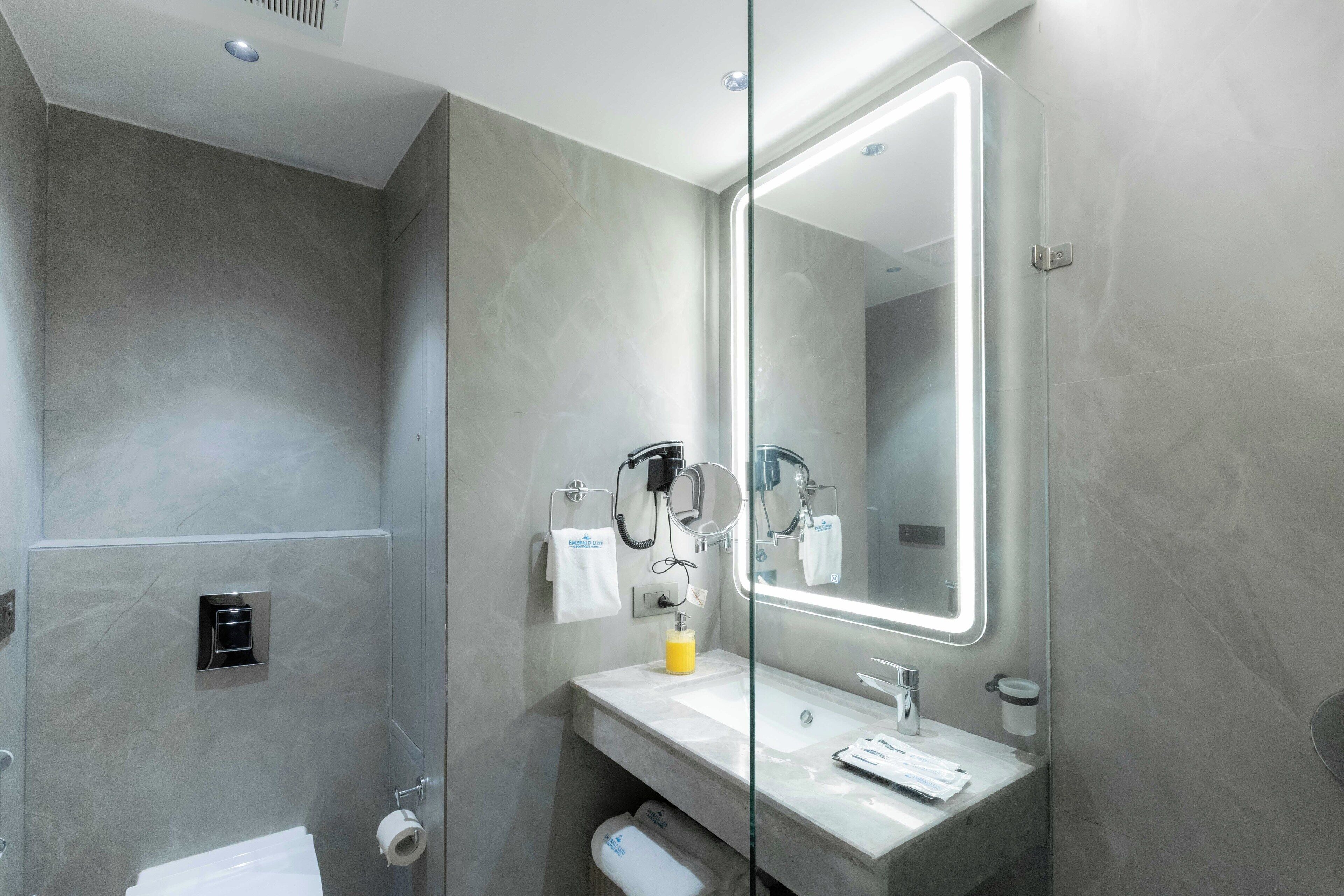Un bagno moderno con cabina doccia in vetro, un mobile lavabo con specchio e un water.