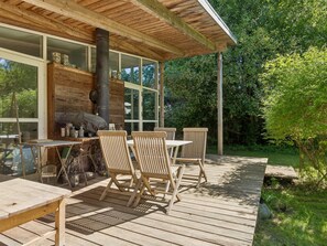 Eine Holzterrasse mit Gartenmöbeln, einem Grill und einem Schornstein.
