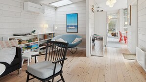 Ein geräumiges Wohnzimmer mit hoher Decke, Holzboden und Blick ins Freie.
